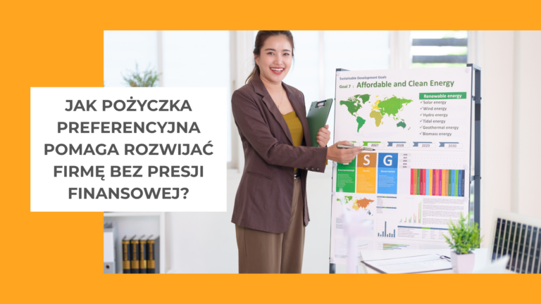 kobieta w brązowej marynarce i pomarańczowej bluzce stoi przy tablicy